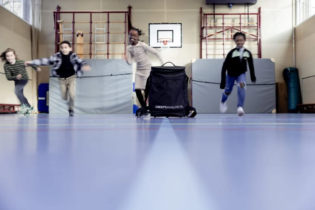 Leerlingen rennen door de gymzaal tijdens een groepsactiviteit