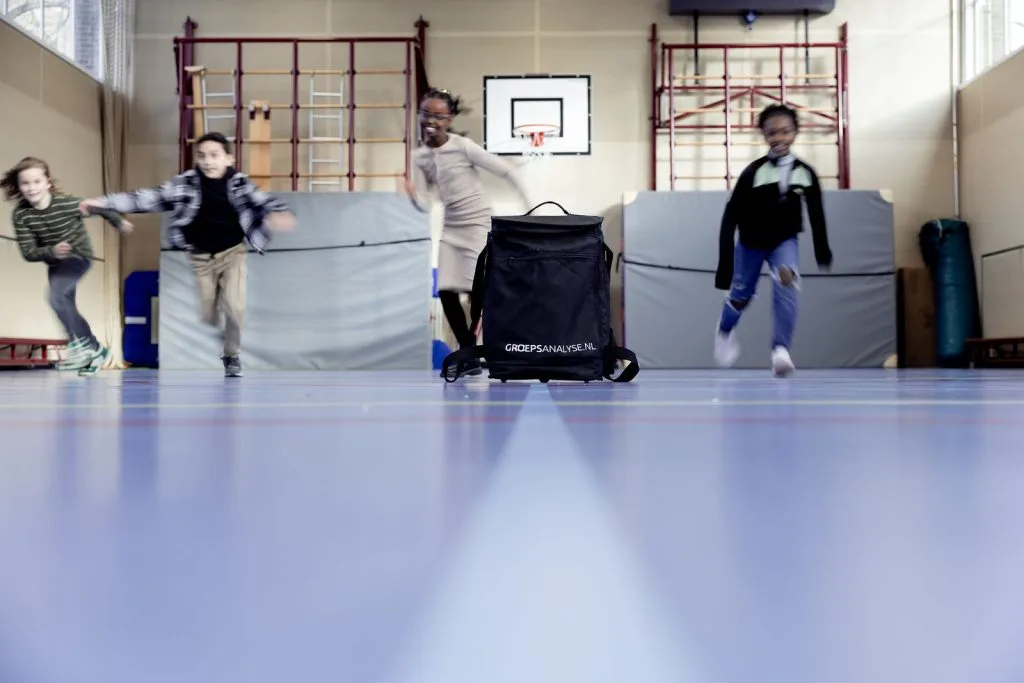 Leerlingen rennen door de gymzaal tijdens een groepsactiviteit